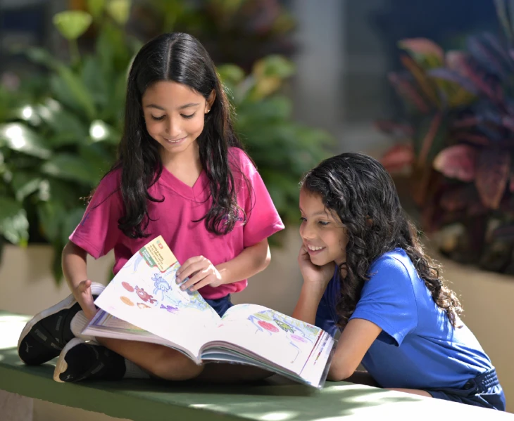 Duas Meninas olhando para um livro de desenhos